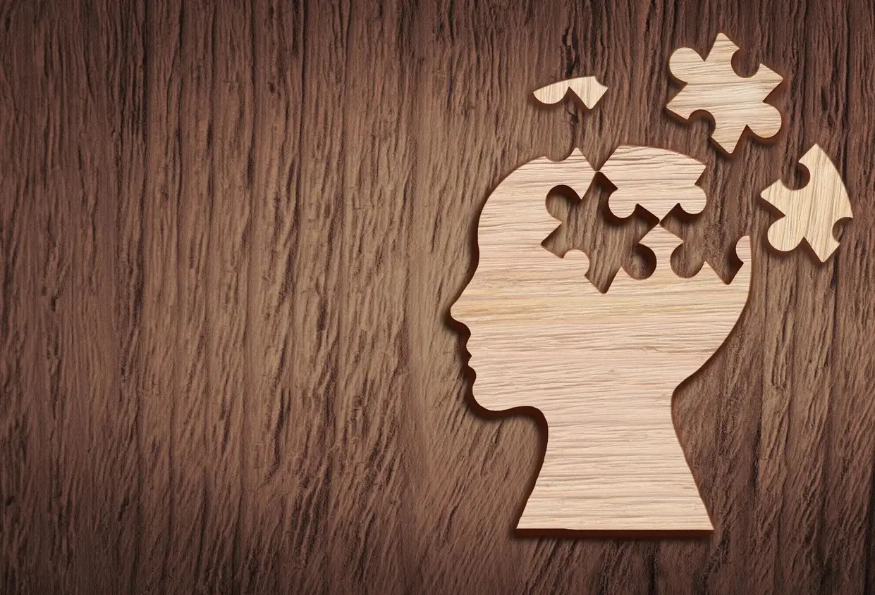 A wooden puzzle piece of a head with a missing part.